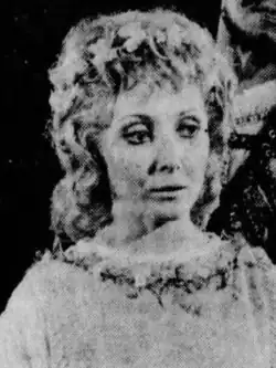 A 71-year-old woman with white hair smiling to the right of the camera.