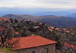 View of a valley with many stone houses along the hill. These are small with red brick roofs.