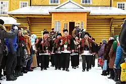 A group of men in traditional costumes exiting a church and singing