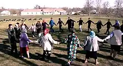 A group of people holding hands and performing a dance in a circle