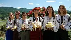 Women holding elaborate objects made of cheese, most in the shape of horses with riders