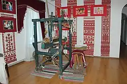 A handloom with embroided towels in the background