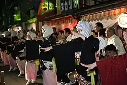 Women in yukata and head scarf dancing.