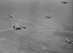 B-24 formation on a mission to Bucharest in 1944. Note the damaged bomber with the smoking engine.