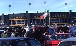 Lambeau Field with parked cars and people in the foreground