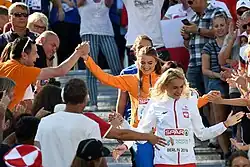 Photo of three athletes walking down a stairs with spectators on both sides