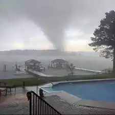 A partly-visible tornado illuminated by a bright flash between two trees