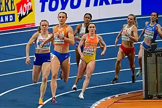 Photo of Lieke Klaver, Henriette Jæger, Paula Sevilla, Lurdes Gloria Manuel, Justyna Święty-Ersetic, and Alice Mangione while running in the bend of a blue 200-metres track