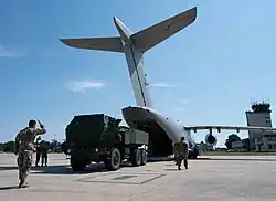 U.S. and Portuguese service members guide an M142 HIMARS out of a Portuguese KC-390 Millennium