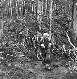 Soldiers in battle gear advance up a hill
