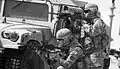 Soldiers take cover behind a HMMWV during live fire training.