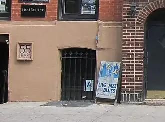 The bottom floor of a building with a sign that says "55 Bar". A sandwich board reads, "live jazz and blues".