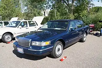 A blue full-size luxury sedan at a car meet.