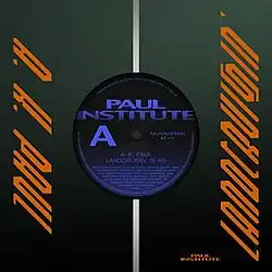 The image mimicks the front of a 7-inch vinyl record package, with a dark green sleeve with a circular cut on the middle. The orange, stylized text "A.K. Paul" appears to its left while the right side contains the word "Landcruisin'" in a similar style. Inside the circular cut is a vinyl label, with a black background, displaying the words Paul Institute, A, 45 rpm, the vinyl catalog number, and song details in smaller font.