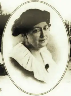 B&W portrait photo of a middle-aged white woman wearing a dark hat, glasses, and a white-collared blouse