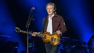 Paul McCartney holding a guitar on stage