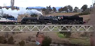 Restored steam locomotive no. 6029 hauling a load test train over the Queanbeyan River bridge