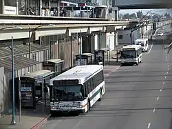 City buses next to an elevated rapid transit station