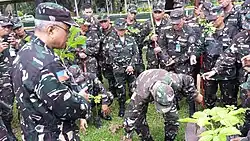A member of the Quezon City TAS Unit demonstrates the actual planting of a sapling while BGen Johnny Macanas AFP - AFP Deputy J-9 looks on.