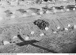 Graves with one marked with a wreath, a shadow of a cross in the foreground