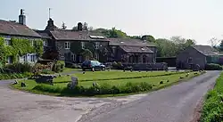 Some cottages with a small village green in front, and a single track road on the right