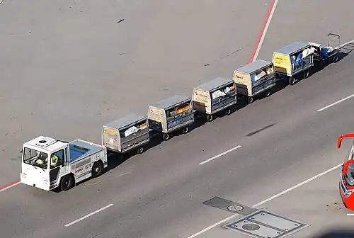 An airport baggage vehicle tows trolleys filled with airmail