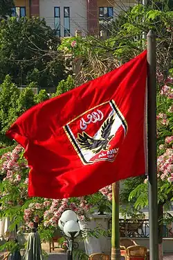 A flag with the crest of Egyptian association football club Al Ahly, on a red background, can be seen.