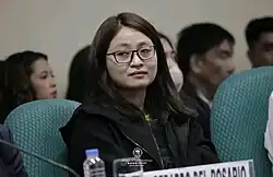 A seated Guo wearing black and looking at something to the left.