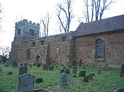 Part of a stone church seen from an angle. At the far end is a battlemented tower, in front of which is a nave with a flat parapet, and part of a chancel with a tiled roof