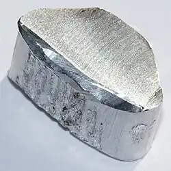 An oblong piece of silvery metal on a glossy surface