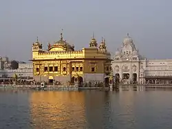 A temple in golden colour with a pool in front