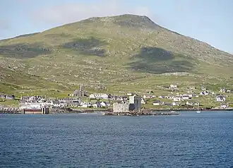 The Village of Castlebay from the sea with Kisimul Castle in the foreground and the heights of Heaval beyond