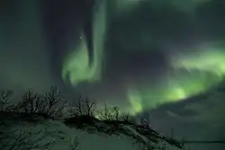 The solar wind moving through the magnetosphere alters the movements of charged particles in the Earth's thermosphere or exosphere, and the resulting ionization of these particles causes them to emit light of varying colour, thus forming auroras near the polar regions.