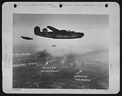 A black and white photograph of 3 planes bombing a city as clouds of smoke emerge; from left to right, Wuchang, the Yangtze River, the Hankou Waterfront and the Hankou Airdrome are marked out