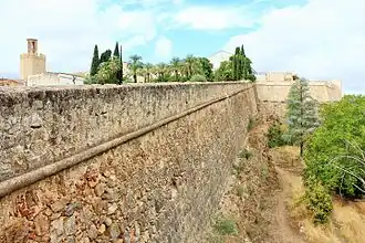 Large raised curtain wall on rock and Espantaperros Tower in the background, to the left