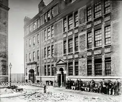 Bear Yard Receiving Workhouse and Casual Wards c1900. The image shows a line of men along the street outside of a large 4-story building, awaiting admission to it.