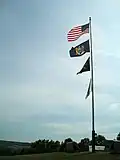 (Top down) American, New York State, Prisoner of War and New York State Office of Parks Recreation and Historic Preservation flags fly atop the hill at the battlefield