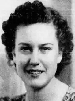 A smiling young white woman with short curly dark hair