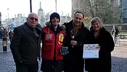 Lord John Bird and Dr Ros Morpeth OBE present bursaries to former and present Big Issue vendors in Trinity Square, Cambridge..