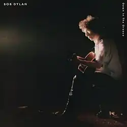 Dylan sitting onstage with a guitar