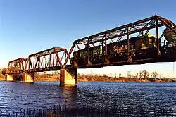 A train crosses a bridge over a wide river.