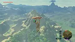 An in-game screenshot of the protagonist Link, paragliding across a vast world.