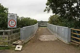 A narrow bridge with galvanised steel panels on the sides