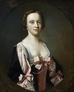 Portrait of a white female wearing a low-cut pink and black dress with white edges