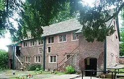 A long brick chapel with rectangular windows and an external staircase at each end