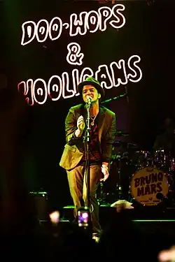 Bruno Mars on stage singing into a microphone