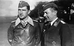 Black-and-white photograph showing half-length view of two uniformed men outdoors, standing next to each other.