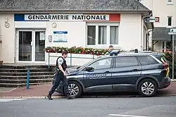 At the side of a road, in the foreground, French gendarmes and, in the background, a Gendarmerie office.