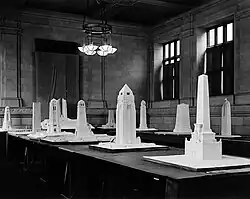 Approximately a dozen monument models sit on tables in a stone-walled room.