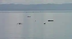 Fishing folks on outrigger canoes on Cancabato Bay, with the San Juanico Strait and Samar island in the background.